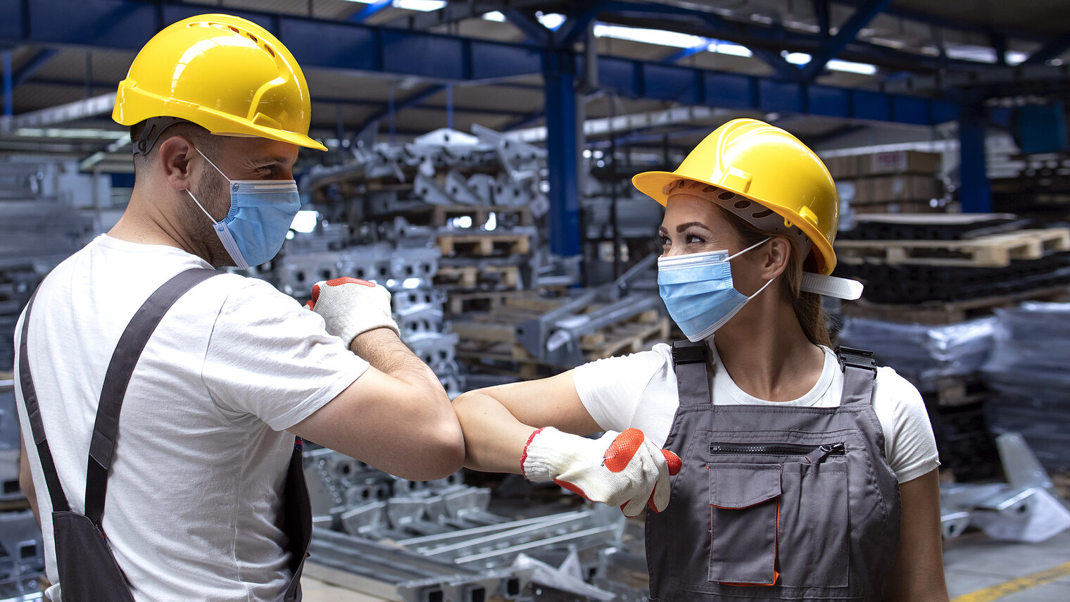 People working at factory touching with elbows and greeting due to corona virus and infection. Employees in factory wearing protection mask. Schlagwort(e): greeting, elbow, elbow greeting, elbow bump, supervisor, manager, worker, people, protection, mask, protection mask, hygienic, face mask, corona, virus, corona virus, COVID-19, prevention, precaution, disease, wearing, epidemic, pandemic, health, healthy, woman, work, industry, industrial, factory, plant, job, occupation, workman, uniform, helmet, hardhat, laborer, production, hall, technical, construction, engineering, business, indoors, working, foreman, manufacturing, engineer, safety measures