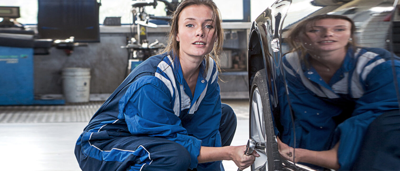 Female mechanic, loosening bolts, to change the tyres on a vehicle for winter and all weather profile tyres Schlagwort(e): tyres, changing, road safety, mechanic, specialist, car, vehicle, rubber, profile, winter, all weather, garage, woman, pretty, overall, coveralls, service, winter tyres, compound, wheels, rim, barrow, bridge, lift, car lift, workshop, customer service, professional, tire, tread, tyre tread, occupation, repair, shop, fix, replacing, exchaniging, maintenance, automotive, automobile