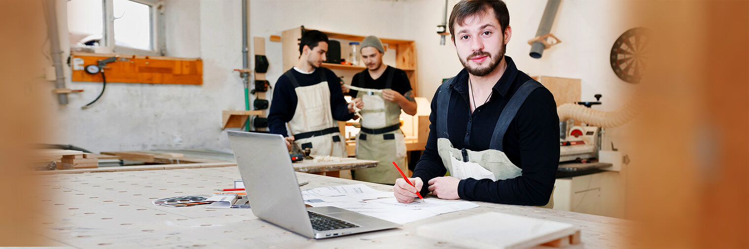 Holzhandwerker in der Werkstatt mit Laptop. Bild: Nadezhda / stock.adobe.com