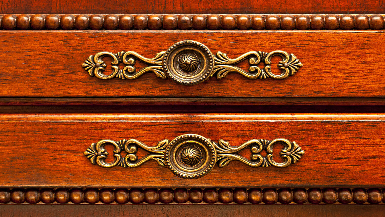 Ornate handles on wooden cabinet doors closeup Schlagwort(e): handles, cabinet, antique, furniture, hardware, knobs, closeup, brass, door, wooden, ornate, fancy, metal, knob, two, decorative, close, detail, details, round, wood, brown, carpentry, craftsmanship, closed, vintage, cherry, red, luxury, doors, decor, woodworking, stained, finished, design, dresser, storage, old, handle, retro, decoration, interior, decorating, pulls