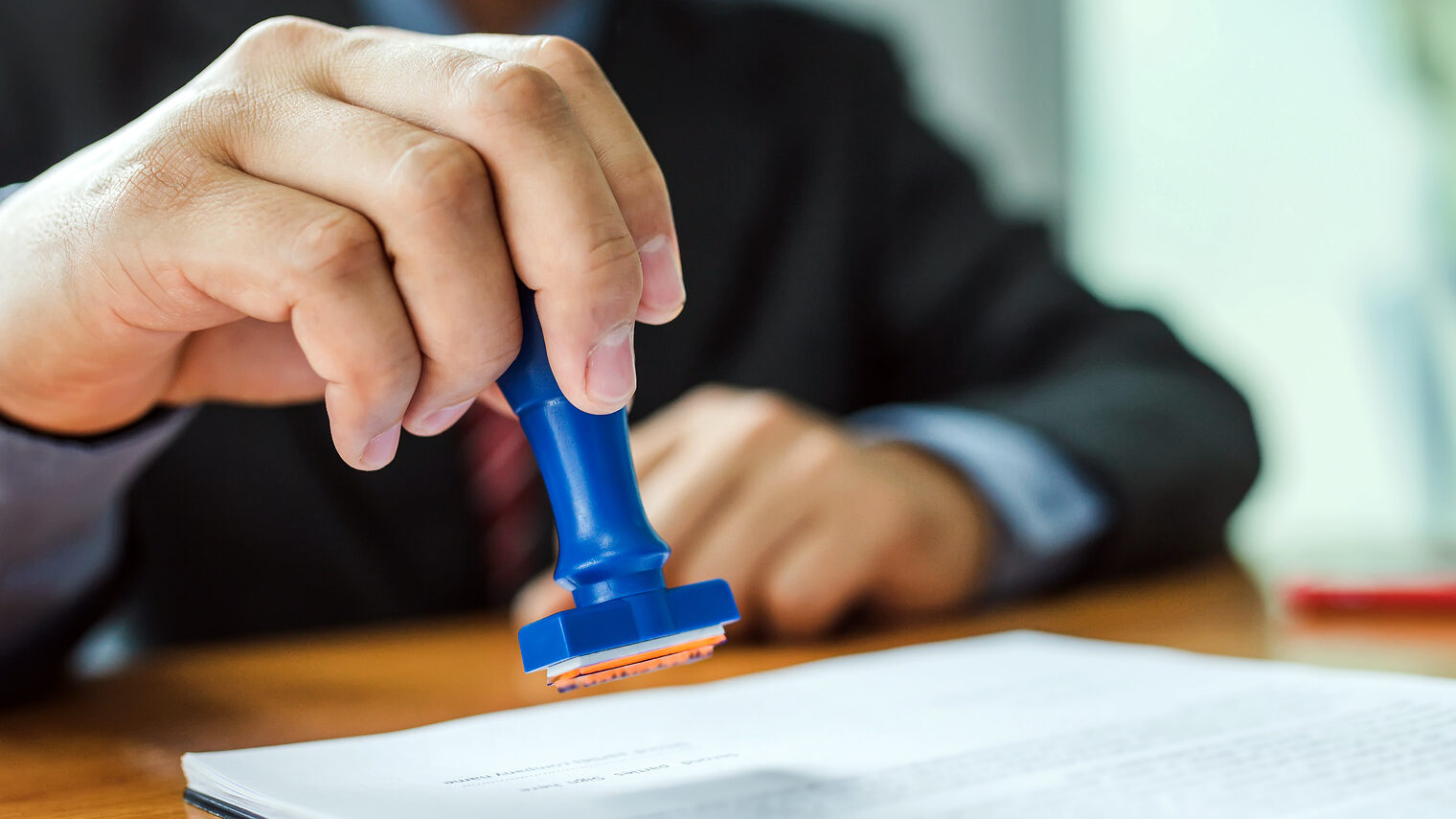 Businessman stamping with approved stamp on document at meeting. Schlagwort(e): agreement, application, approval, approve, attorney, authority, business, businessman, certificate, certification, certified, certify, clerk, concept, contract, desk, document, documents, finance, financial, form, hand, ink, law, lawyer, legal, manager, meeting, notary, office, official, paper, paperwork, people, permit, person, pressure, professional, public, record, rubber, seal, signature, signing, stamp, stamper, success, text, work, workplace, agreement, application, approval, approve, attorney, authority, business, businessman, certificate, certification, certified, certify, clerk, concept, contract, desk, document, documents, finance, financial, form, hand, ink, law, lawyer, legal, manager, meeting, notary, office, official, paper, paperwork, people, permit, person, pressure, professional, public, record, rubber, seal, signature, signing, stamp, stamper, success, text, work, workplace