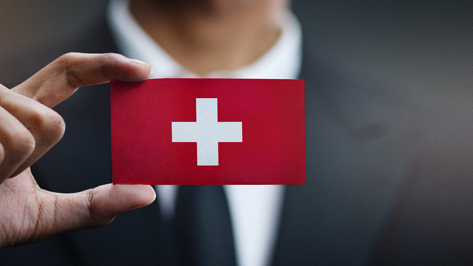 Businessman Holding Card of Switzerland Flag Schlagwort(e): business, businessman, card, concept, corporate, country, flag, hand, holding, man, nation, office, professional, showing, sign, suit, symbol, switzerland, swiss confederation, none, swiss, switzerland flag