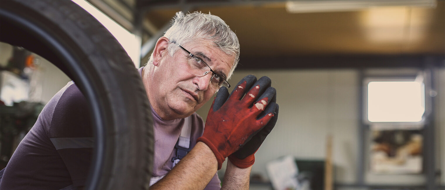 Älterer nachdenklicher Handwerker in der Kfz-Werkstatt. Bild: liderina / stock.adobe.com