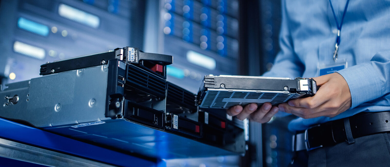 In the Modern Data Center: IT Engineer is Holding New HDD Hard Drive Prepared for Installing Hardware Equipment into Server Rack. IT Specialist Doing Maintenance and Updating Hardware. Schlagwort(e): administrator, backup, big, center, centre, cloud, cluster, component, components, computer, computing, connection, data, data center, database, datacenter, diagnostics, electronics, engineer, equipment, fixing, future, hard drive, hardware, information, innovation, installing, internet, mainframe, maintenance, male, man, muffs, network, networking, parts, person, rack, repair, repairing, room, safety, server, service, solution, specialist, storage, support, system, technician, technology, tools, worker, working