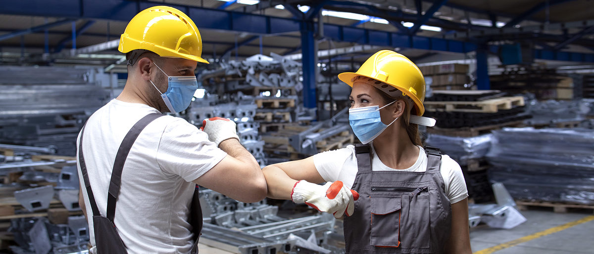People working at factory touching with elbows and greeting due to corona virus and infection. Employees in factory wearing protection mask. Schlagwort(e): greeting, elbow, elbow greeting, elbow bump, supervisor, manager, worker, people, protection, mask, protection mask, hygienic, face mask, corona, virus, corona virus, COVID-19, prevention, precaution, disease, wearing, epidemic, pandemic, health, healthy, woman, work, industry, industrial, factory, plant, job, occupation, workman, uniform, helmet, hardhat, laborer, production, hall, technical, construction, engineering, business, indoors, working, foreman, manufacturing, engineer, safety measures