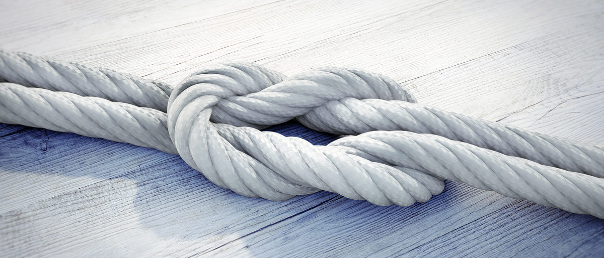 Kreuzknoten weißes Seil auf weißem Holz, Sicherung, Versicherung. Bild: peterschreiber.media / stock.adobe.com