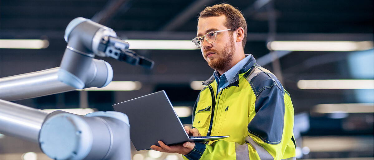 Mann programmiert einen Roboterarm. Bild: Gorodenkoff / stock.adobe.com