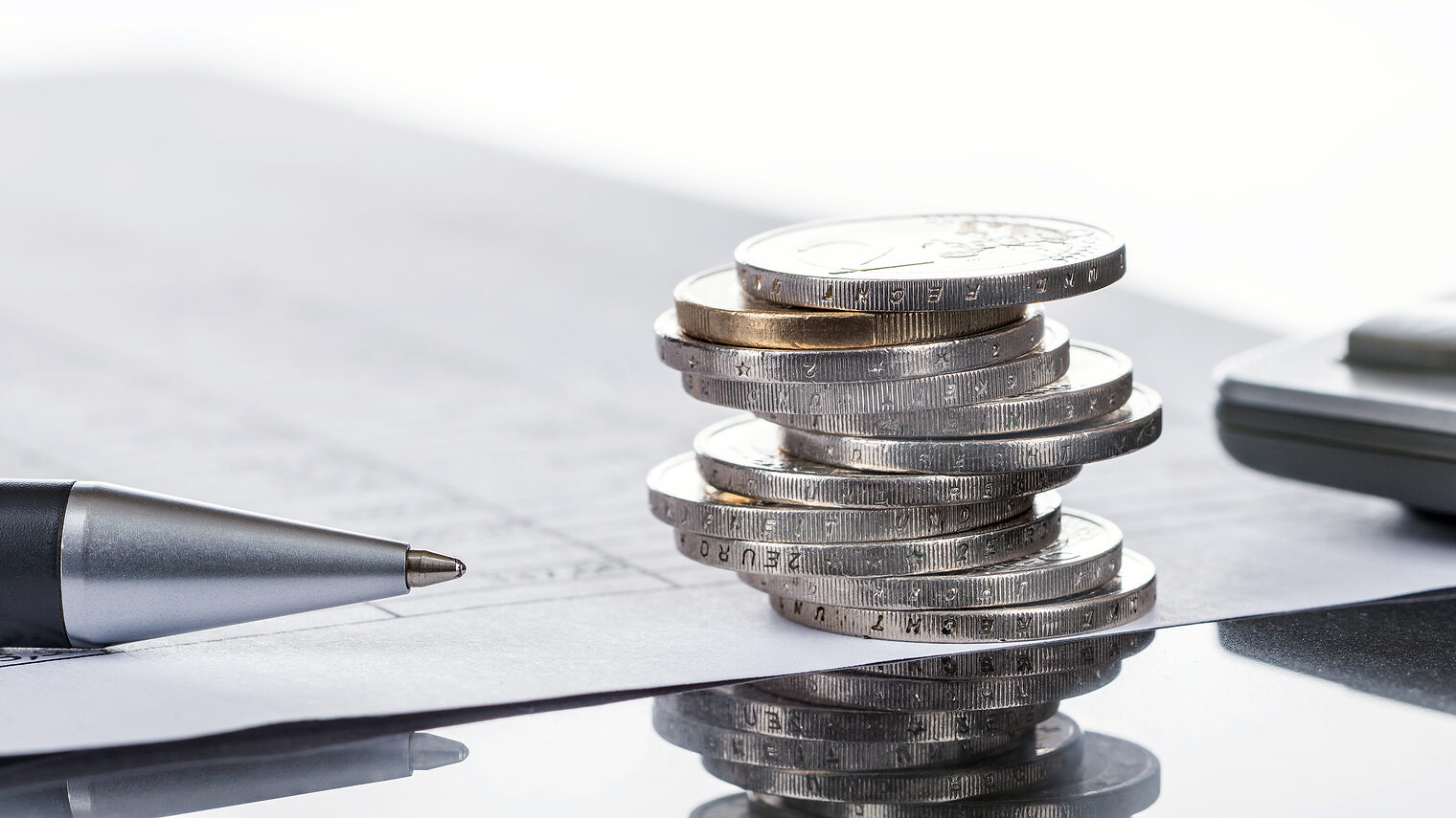 Finanzen, Euro, Münzstapel auf Tabellen mit Stift und Taschenrechner, Bild: v.poth / stock.adobe.com