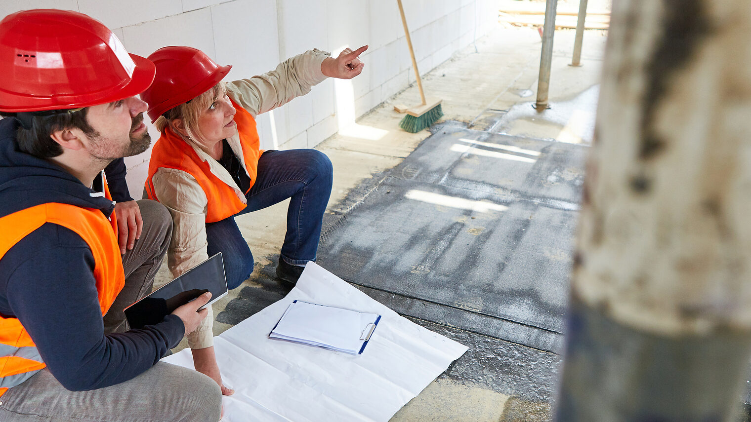 Architekten-Team mit Grundriss auf der Baustelle im Rohbau bei der Planung der Bauarbeiten, Sachverständige, Gutachter. Bild: Robert Kneschke / stock.adobe.com
