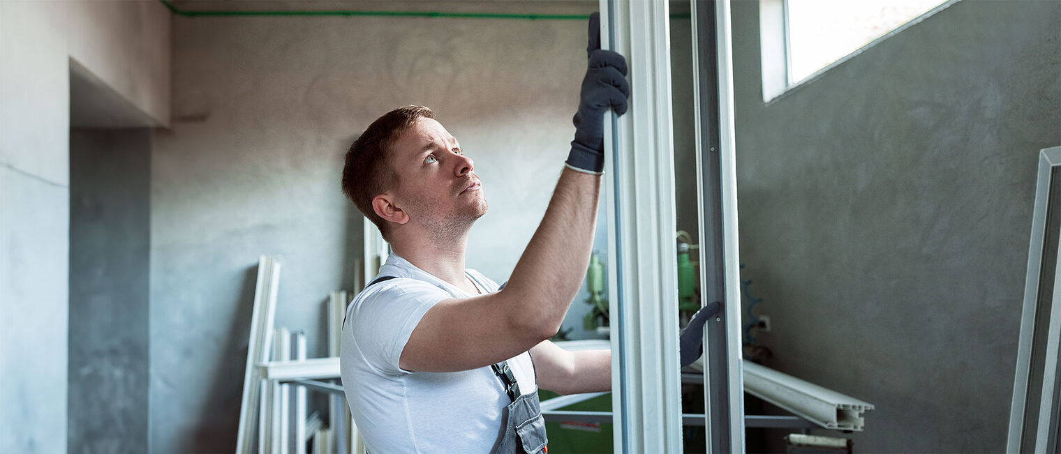 Handwerker mit Metall- und Plastikprofilen auf einer Baustelle oder in einer Werkstatt. Bild: stock.adobe.com / didesign (bearbeitet mit KI)