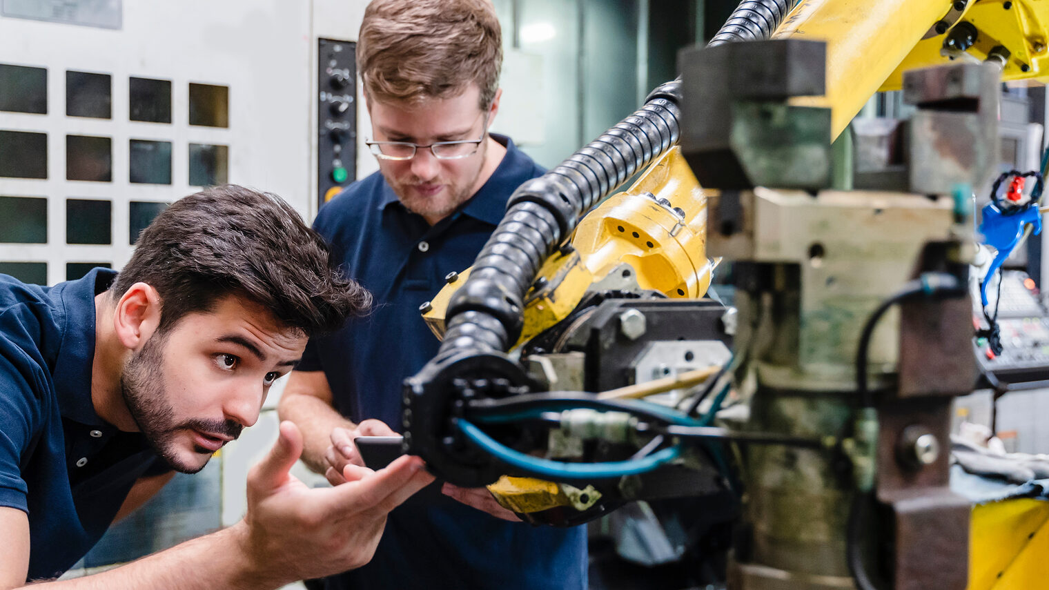 Junger Mann untersucht Roboterarm. Bild: tunedin / stock.adobe.com