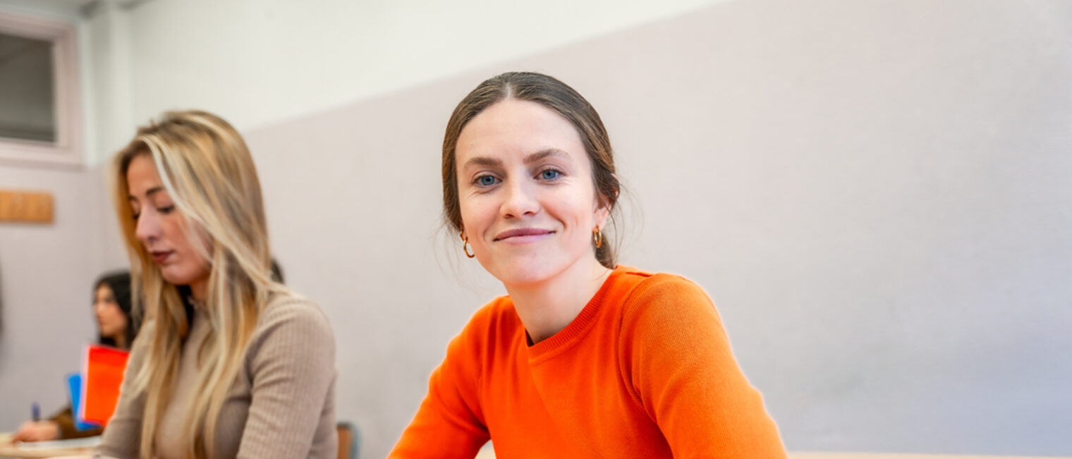 Zwei junge Frauen machen sich Notize während eines Weiterbildungskurses. Eine junge Frau fertigt Mitschriften während einer Fortbildung an.