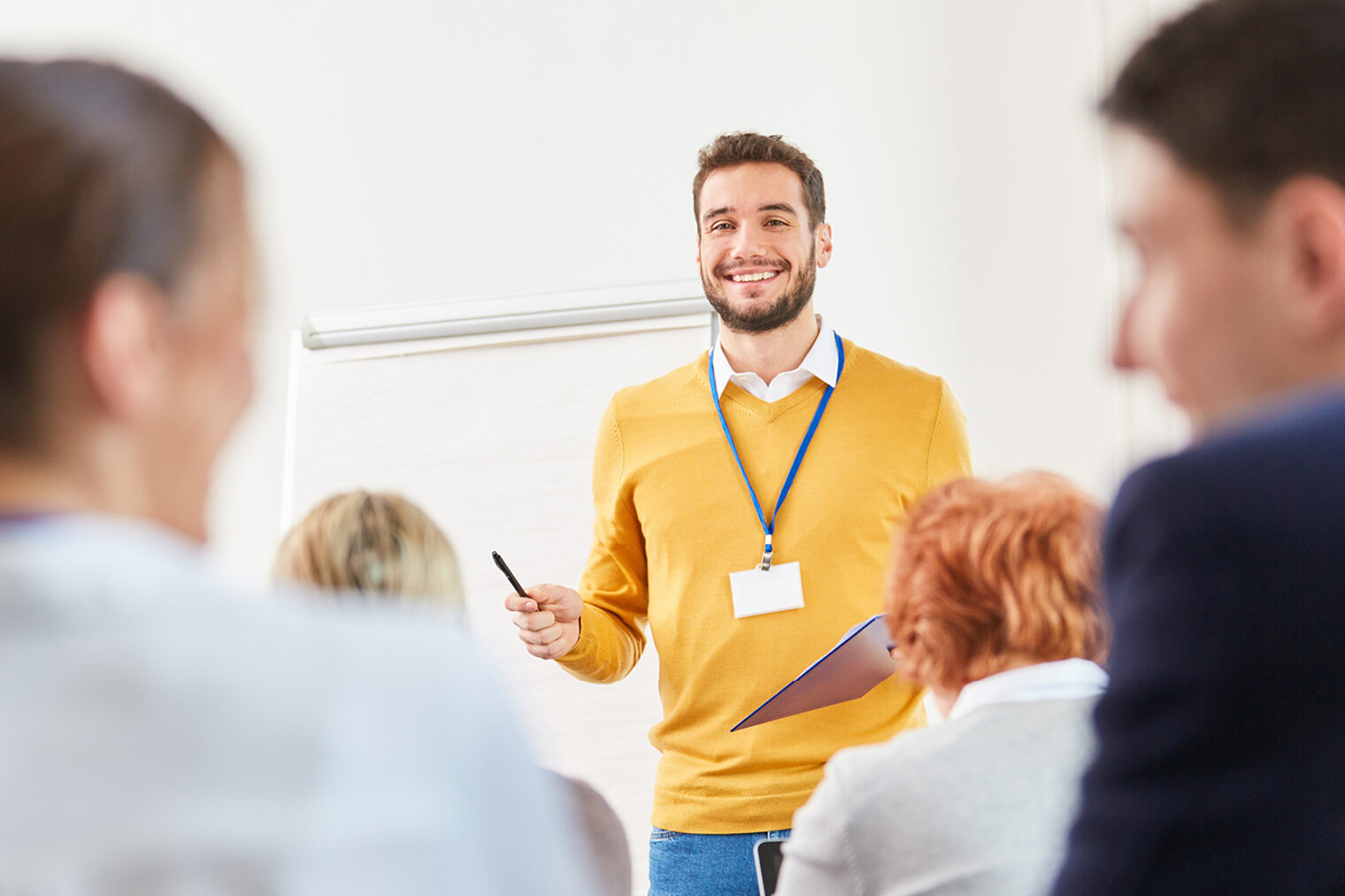 Ein Mann hält ein Referat. Fortbildungssituation: Ein lächelnder Dozent spricht in einem Seminar.