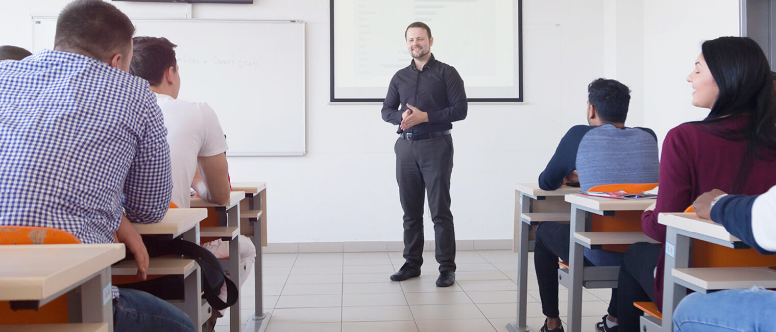 Ein Kursteilnehmer spricht vor einer Gruppe von Personen. Fortbildungssituation: Ein Dozent oder Seminarteilnehmer spricht vor einer Gruppe von Personen.