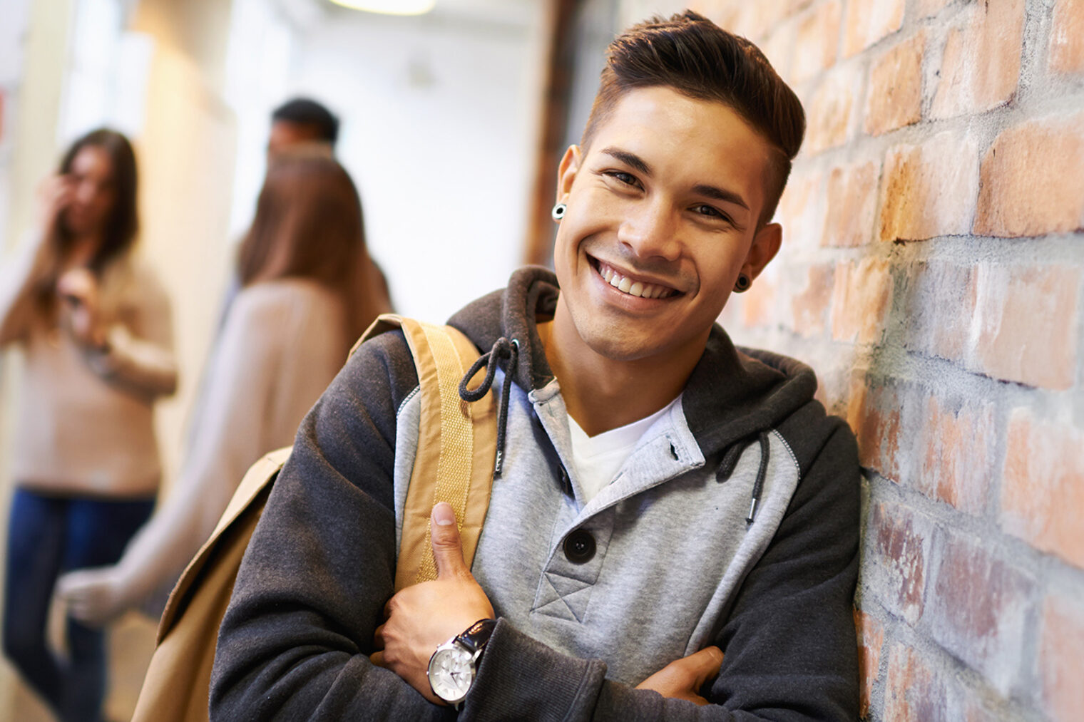 Ein junger Student lehnt in einer Schule an einer Wand.