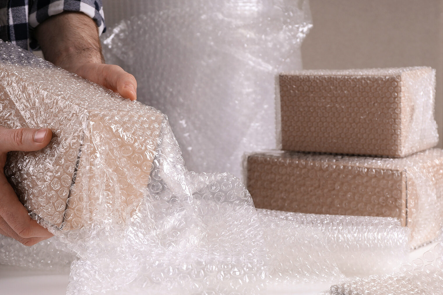 Ein Mann verpackt einen Karton mit Luftpolsterfolie. 