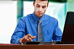 Mann im Büro mit Rechner. Bild: fotolia.com - Minerva-Studio