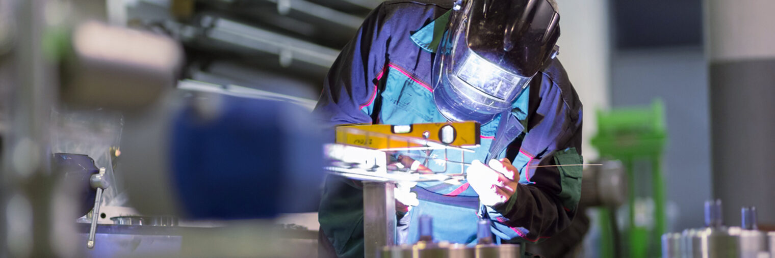 Industrial worker with protective mask welding inox elements in steel structures manufacture workshop. Schlagwort(e): welder, industry, worker, inox, steel, metal, craftsman, industrial, craft, manufacturing, engineering, welding, factory, skill, man, mask, safety, spark, protection, flash, manufacture, metalwork, weld, laborer, equipment, welded, labor, work, occupation, skilled, production, repair, torch, fabrication, manual, technical, fabricate, assembly, tool, helmet, iron, connect, workwear, manual worker, manufacturing plant, protective workwear, welding torch, gas, join, construction