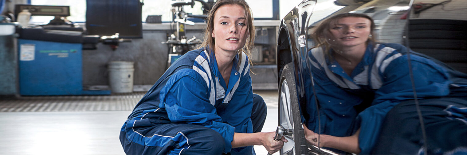 Female mechanic, loosening bolts, to change the tyres on a vehicle for winter and all weather profile tyres Schlagwort(e): tyres, changing, road safety, mechanic, specialist, car, vehicle, rubber, profile, winter, all weather, garage, woman, pretty, overall, coveralls, service, winter tyres, compound, wheels, rim, barrow, bridge, lift, car lift, workshop, customer service, professional, tire, tread, tyre tread, occupation, repair, shop, fix, replacing, exchaniging, maintenance, automotive, automobile