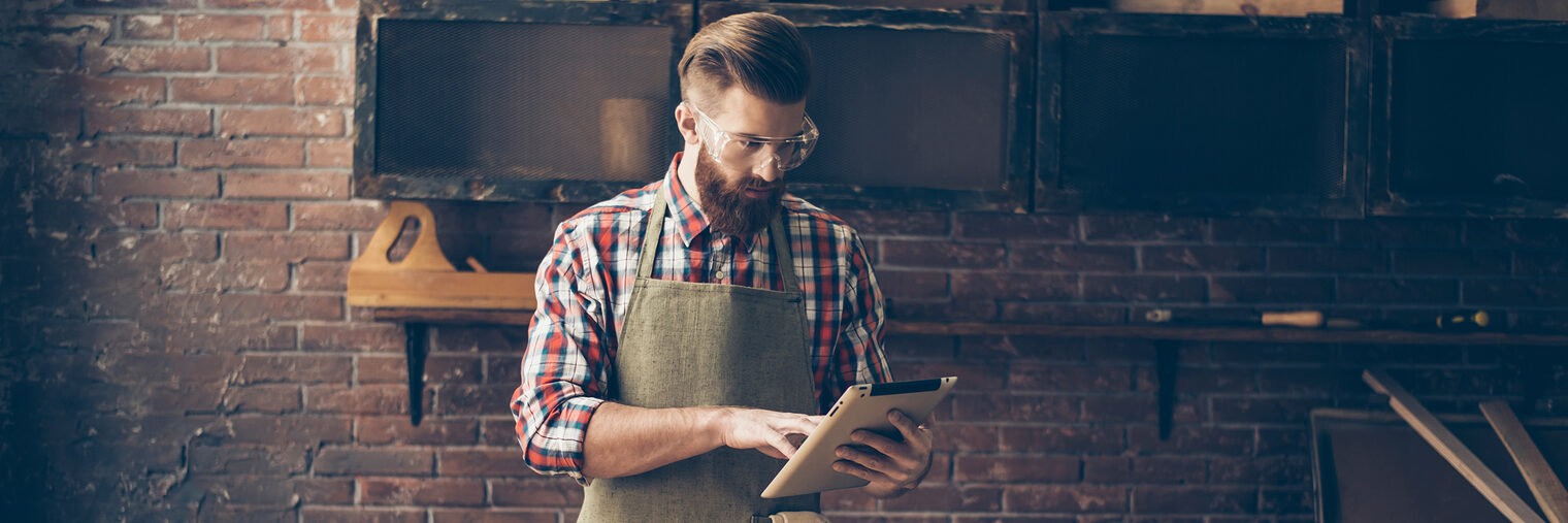 handsome cabinetmaker look at digital tablet Stylish craftsman with brutal hairstyle and saved glasses work at his workplace Schlagwort(e): apron, artisan, beard, builder, building, cabinet-maker, cabinetry, carpenter, carpentry, chisel, construction, constructor, craft, craftsman, diy, engineer, equipment, furniture, garage, hand, handicraftsman, handmade, hardwood, hobby, home, indoors, instrument, interior, joiner, lumber, male, man, manufactory, master, plane, profession, repair, restoration, shop, tablet, technology, timber, tool, wood, woodman, woodworker, work, worker, workplace, workshop