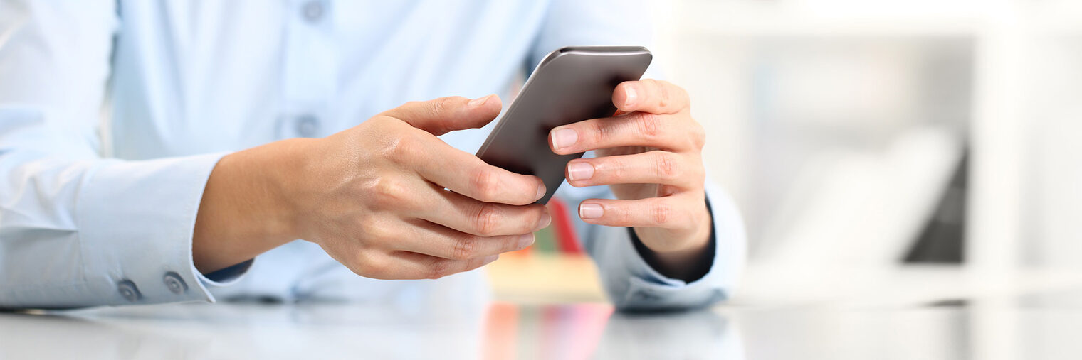 Hand mit Smartphone im Büro. Bild: visivasnc / fotolia.com