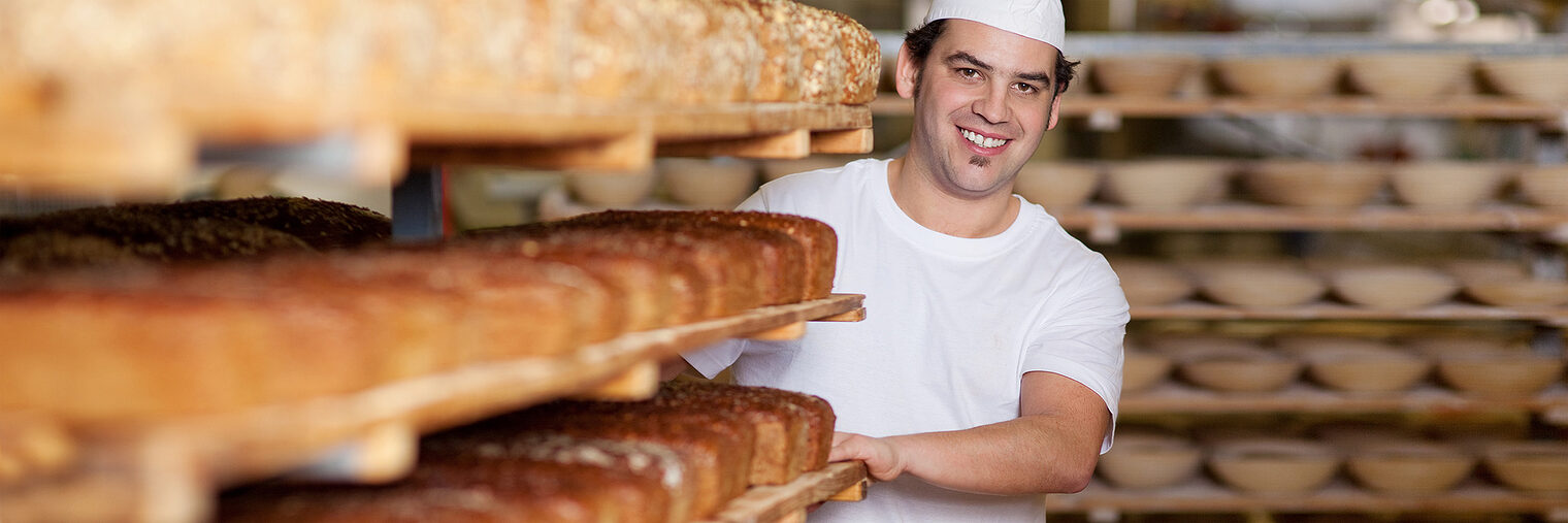 Bäcker in der Backstube mit einem Wagen voller Brote. Bild: contrastwerkstatt / fotolia.com