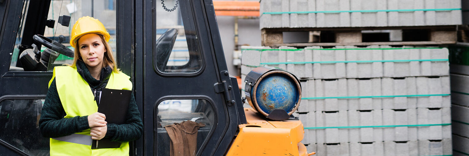 Frau vor einem Gabelstapler. Bild: Halfpoint / stock.adobe.com