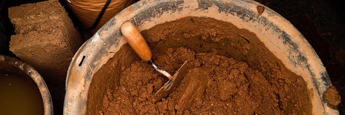 Eine Schüssel mit einer Lehmmischung für den Lehmbau (A bowl with a clay mixture for the clay building) Schlagwort(e): Lehm, Baustoff, Mischung, Lehmbau, Lehmziegel, Schüssel, Kelle, Ton, Feinstsand, Sand, feucht, Wärmedämmung, schadstofffrei, hautfreundlich, regulierend, recycelbar, umweltfreundlich, wärmespeicher, Tradition (Clay, construction material, mixture, earthen, Adobe, bowl, ladle, clay, very fine sand, Are, damp, insulation, pollution-free, hypoallergenic, regulating, recyclable, environmentally friendly, heat storage, tradition)