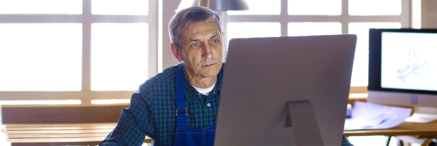 Älterer Handwerker / Meister im Büro am Computer. Bild: lenetsnikolai / stock.adobe.com