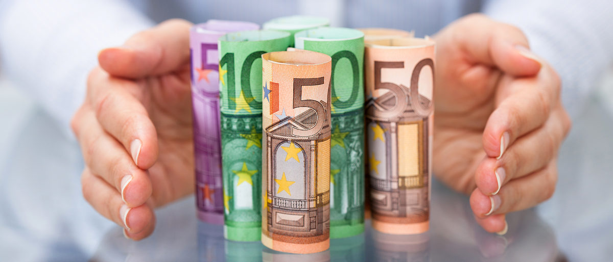 Close-up Of Hand Protecting Rolled Up Euro Banknote Schlagwort(e): money, paper, people, insurance, success, finance, glass, green,