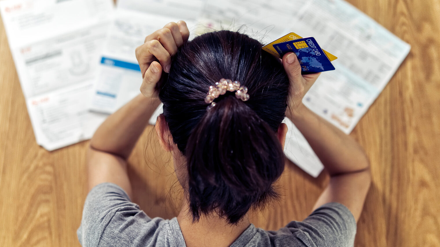 Top view of stressed young sitting Asian woman hands holding the head worry about find money to pay credit card debt and all loan bills. Financial problem concept. Schlagwort(e): adult,asian,bank,bankrupt,bankruptcy,bills,broke,business,card,c